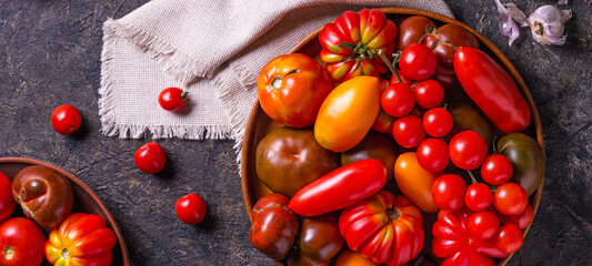 The harvest of assorted tomatoes, banner. Colorful organic tomatoes on a large dish. Tomatoes different varieties. Top view