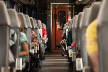 Seats of a passenger car in a European train with people seating on it, with a single lobby in the...