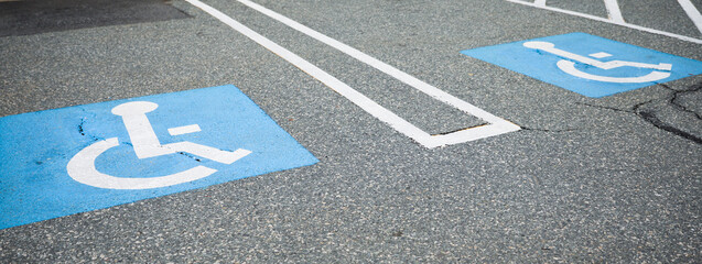 The blue handicap sign on the street is a universal symbol for accessibility and mobility aid for individuals with disabilities, representing equal opportunities and inclusion - obrazy, fototapety, plakaty
