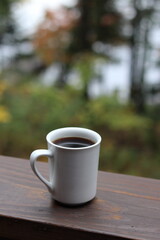 Obraz na płótnie Canvas Cup of coffee on wooden deck in autumn