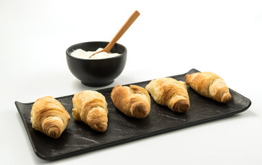 Traditional rolled dough called Kiflice served wuth yogurt on black plate and white background