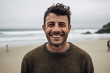 Portrait of a handsome young man smiling at the beach in autumn