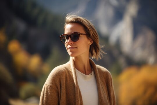 Portrait of a beautiful woman in sunglasses on the background of mountains