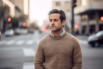 Handsome young man in an urban context. He is wearing a brown sweater.