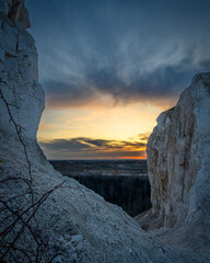 View of the sunset over the city through a gap between two chalk cliffs