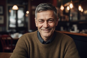 Portrait of a smiling senior man sitting in a cafe, looking at camera
