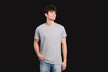 Man wearing light gray t-shirt on black background. Mockup for design