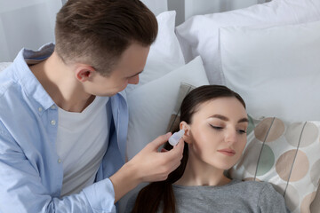 Man dripping medication into woman's ear at home
