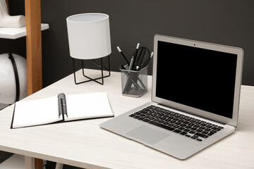 Cozy workplace with laptop and stationery on desk. Home office