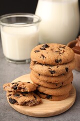 Stack of delicious chocolate chip cookies and milk on grey table