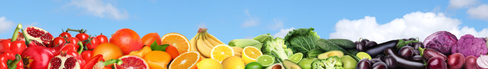 Many different fresh fruits and vegetables against blue sky with clouds. Banner design