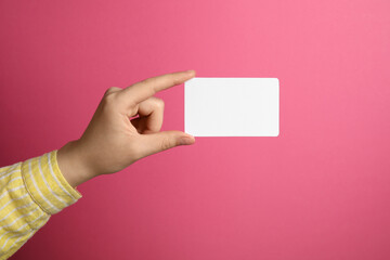 Woman holding blank gift card on pink background, closeup