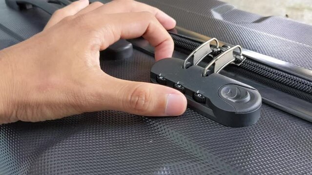 man hands unlocking a code padlock on a suitcase