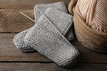 Soft colorful yarns, knitted socks and metal needles on wooden table