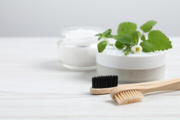 Fototapeta na wymiar Toothbrush, dental products and herbs on white wooden table, closeup. Space for text