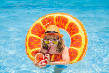 Child in sunglasses and summer hat drink summer cocktail and floating in pool. Kids summer vacation. Children floating in water pool. Children playing and active leisure, swimming pool concept.