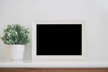 close up of  white wood frame and artificial flower in pot on shelf and  white concrete wall background with clipping path