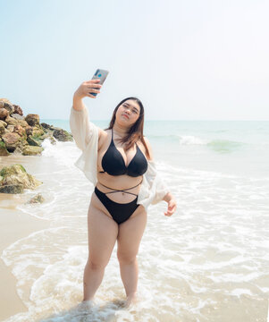 Portrait young woman asian chubby cute beautiful taking pictures with smartphone in bikini black sexy front viewpoint tropical sea beach white sand clean and bluesky calm Nature ocean Beautiful wave