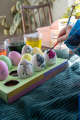 Watercoloring boiled eggs for Easter; toddler uses small brush to decorate 