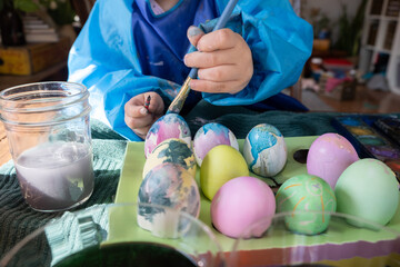 2 year old paints Easter eggs with watercolor and craft paint; fine motor skill development