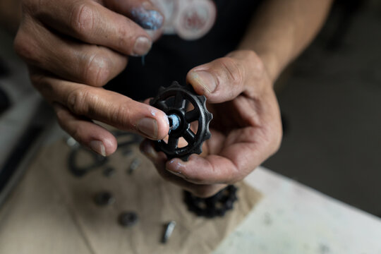 Man lubricating a pulley of a bicycle derailleur system