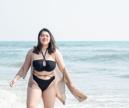 Portrait young woman asian chubby fat cute beautiful one person in bikini black sexy frontview tropical sea beach white sand clean and blue sky background calm nature ocean wave water travel fun happy