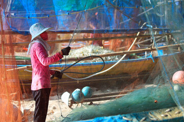 woman cleaning fishing net ,after be back from fishing in the province of Phatthalung-Thailand