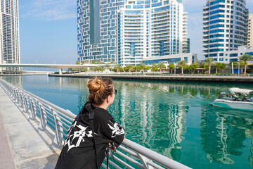 young beautiful woman walking along Dubai Marina in Dubai, UAE