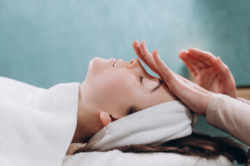 The beautician makes a deep facial massage to a young woman. Face massage technique against aging. Close-up.