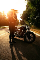 Full body shot, attractive girl taking off biker helmet after the ride, sunset in background 