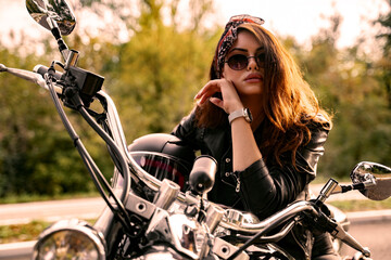 Fototapeta na wymiar Young biker girl with bandana, posing on motorbike and looking at camera
