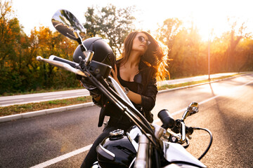 Amazing attractive girl taking off biker helmet after the ride, sunset in background 