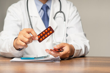 Doctor in a uniform holding tablets in a blister pack while seated in the hospital