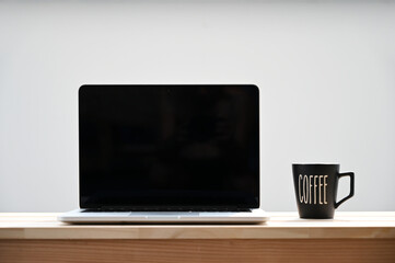 laptop screen and coffee cup on wooden table, minimalist style.
