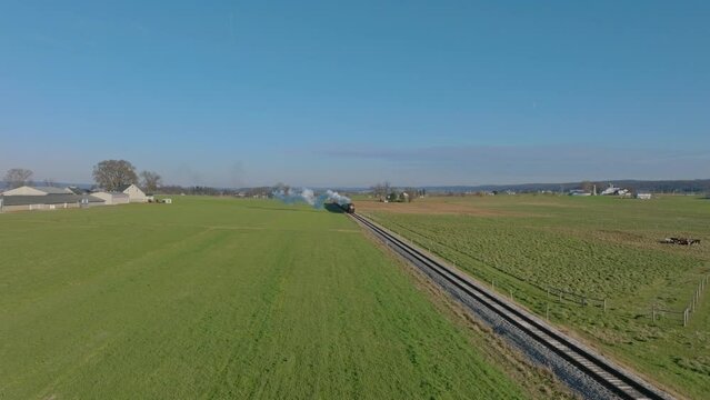 Drone View of Cows and Farmlands With a Single RR Track and a Steam Train Approaching Blowing Smoke and Steam