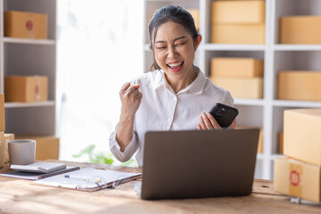 Portrait of Starting Asian female small businesses owners SME entrepreneur working at Laptop in home Warehouse, online marketing, packing boxes, SME sellers, concept, e-commerce team, online sales.	