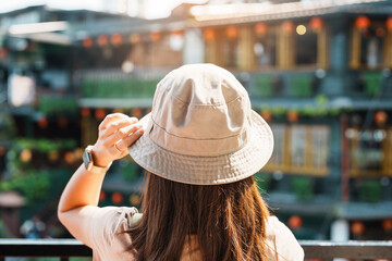 woman traveler visiting in Taiwan, Tourist with hat and backpack sightseeing in Jiufen Old Street village with Tea House background. landmark and popular attractions near Taipei city. Travel concept
