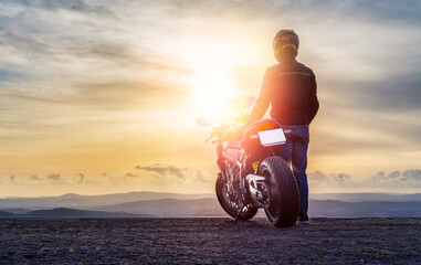 Biker male  and Motorcycle at sunset - Copy space - obrazy, fototapety, plakaty