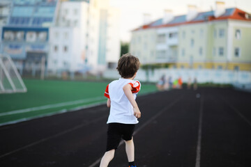The child goes in for sports at the stadium. The boy is training before playing football.