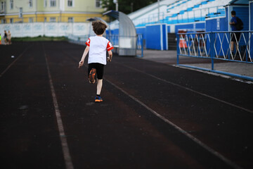 Fototapeta na wymiar The child goes in for sports at the stadium. The boy is training before playing football.