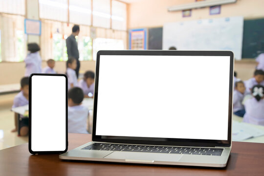 Front view, blank screen of black digital laptop and smartphone with tablet on the wood table. Education software website technology ads concept.