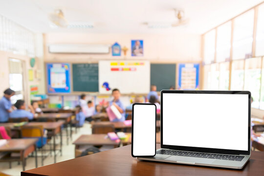 Children students in classroom background. Education software website technology ads concept. Front view, blank screen of black digital laptop and smartphone