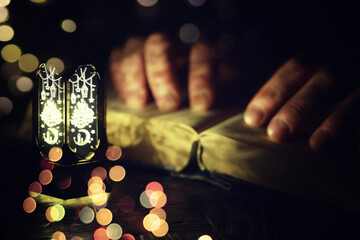 Ramadan Kareem background. Ornamental Arabic lantern glowing and the holy book of Quran.