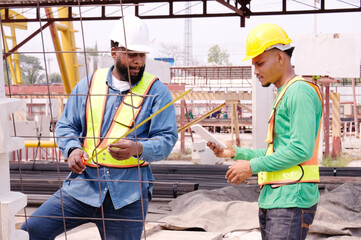 Engineers and construction workers using tape measure at construction site.