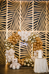 Arch decorated with brown, white and golden balloons, text baby. Trendy cake with figure angel....
