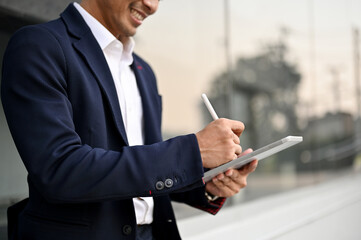 An Asian businessman using his tablet while walking in a city. Urban lifestyle concept