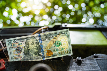One hundred us dollars on a diesel engine of a minitractor close-up. Money and the agricultural...