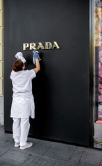 Cleaning services. A woman washes the facade of a building with a wet rag. Cleaning services -...