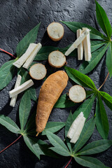 pile of cassava fruit and cassava flour on a background of rustic and dark texture (Manihot esculenta)