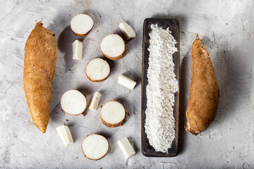 pile of cassava root and cassava flour on a gray and white textured background (Manihot esculenta)